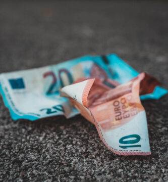 Imagen con dos billetes de euro posados sobre asfalto