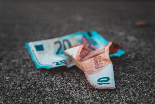 Imagen con dos billetes de euro posados sobre asfalto