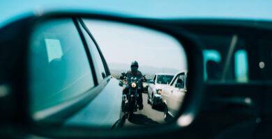 Motocicleta reflejada en el retrovisor de un coche